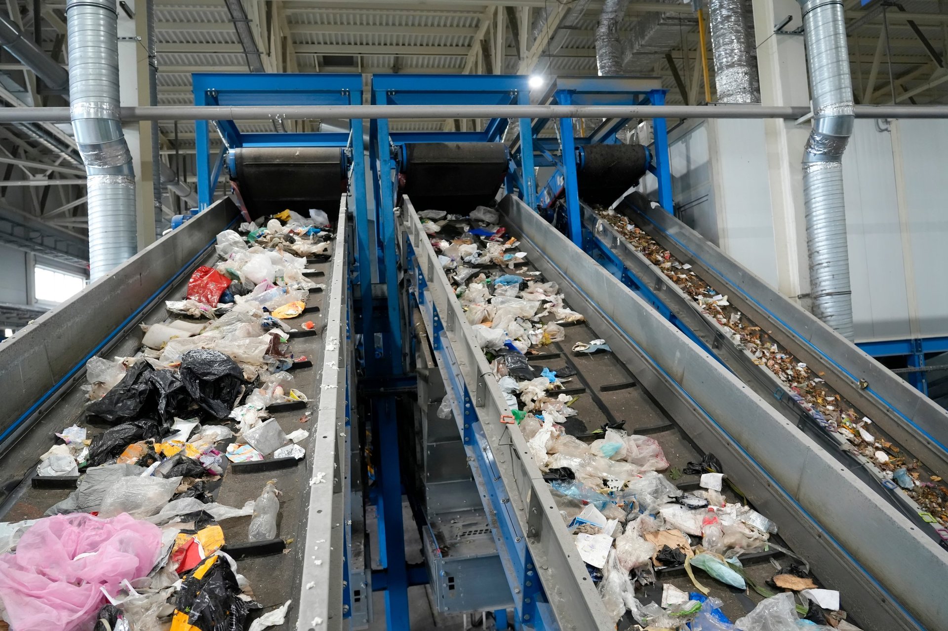An industrial scene inside a waste management facility showcases multiple conveyor belts carrying a diverse array of refuse